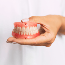 A woman holding a set of dentures